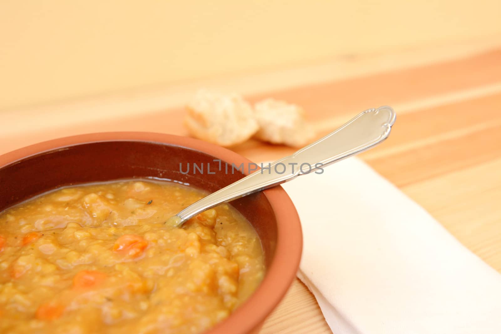 Closeup of chunky vegetable soup with pieces of bread roll