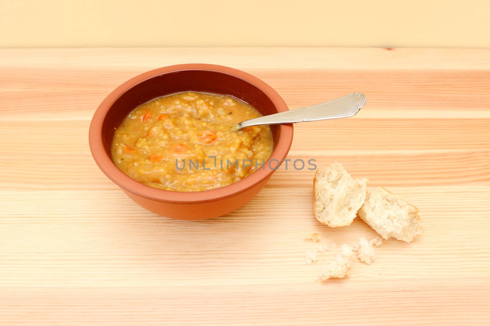 Vegetable soup on wooden table with remainder of bread roll