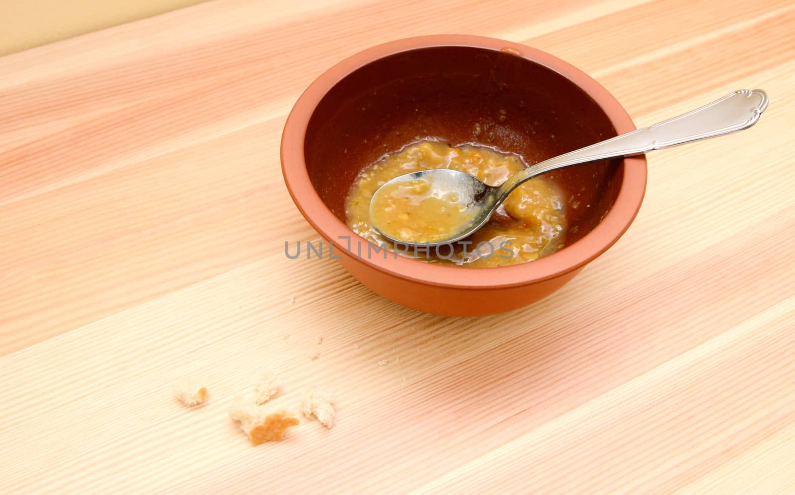 Emptied bowl of vegetable soup with bread crumbs on the table