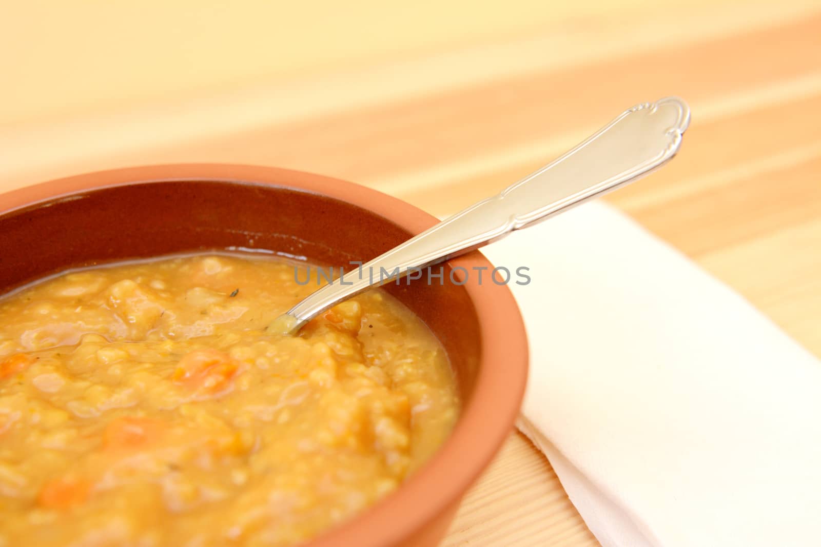 Closeup of hearty vegetable and lentil soup on a wooden table