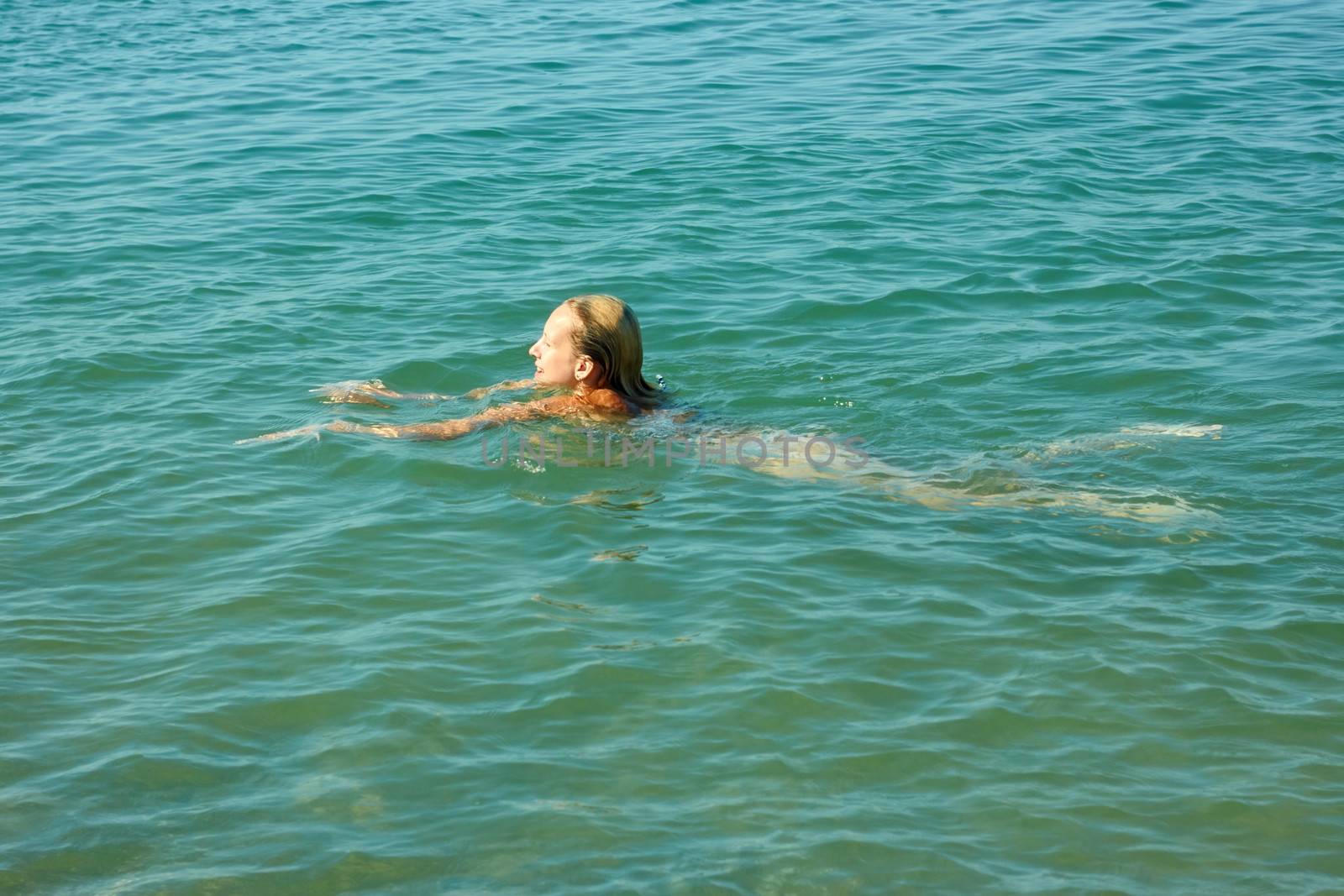 Teenage girl swimming in sea water in warm sunny weather