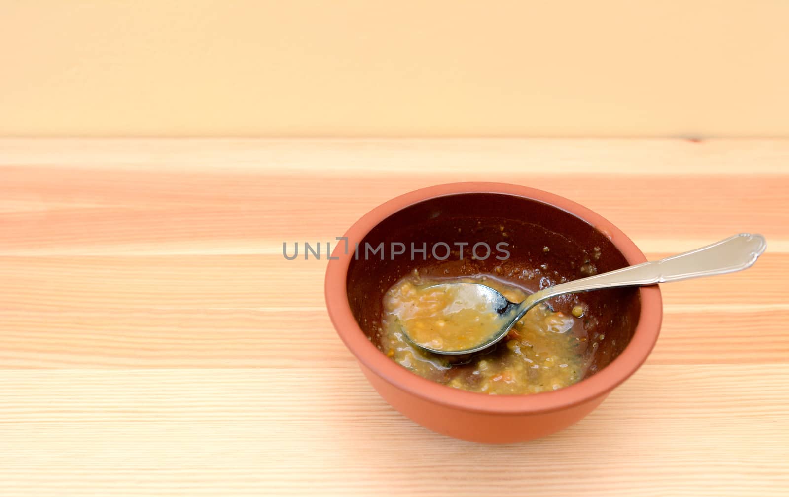 Empty bowl of soup with a spoon on a wooden table with copy space