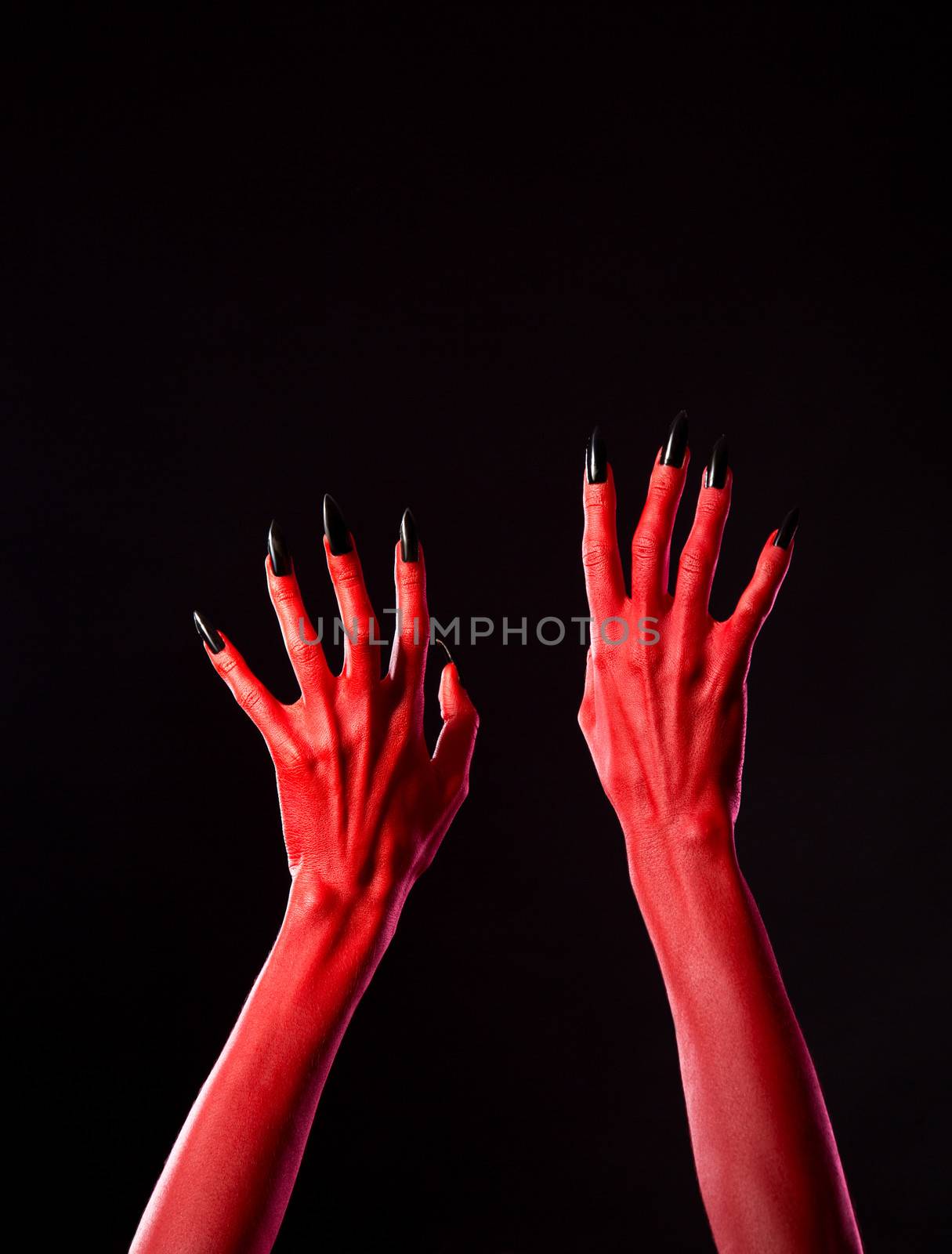 Red spooky devil hands with black nails, Halloween theme, studio shot on black background 