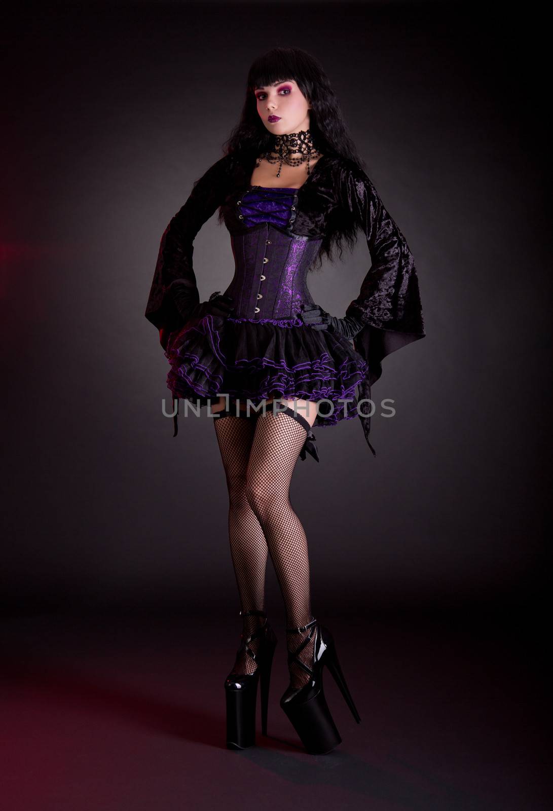 Sexy young woman in black and purple costume wearing extra high heels  