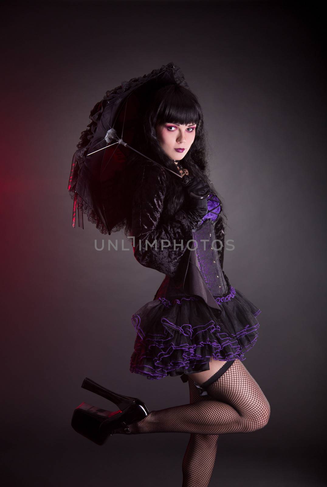 Portrait of gothic Lolita girl with umbrella, studio shot on black background 