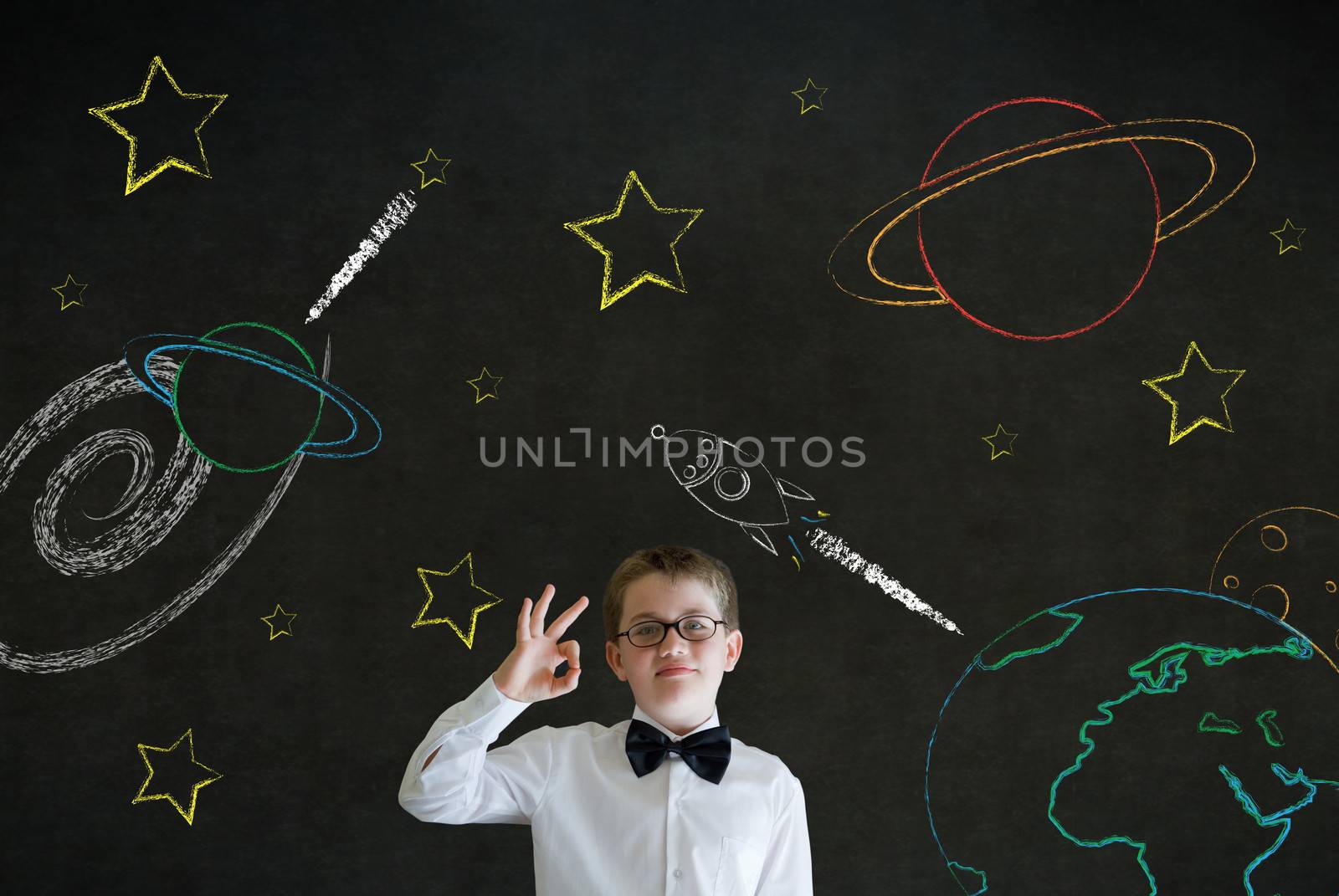 All ok or okay sign boy dressed up as business man with chalk universe planet solar system on blackboard imagining space travel