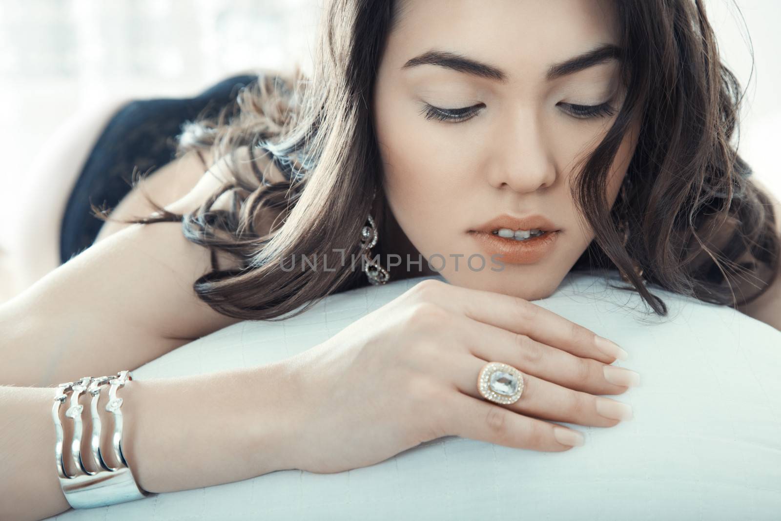 Brunette lady with jewelry laying on the bed