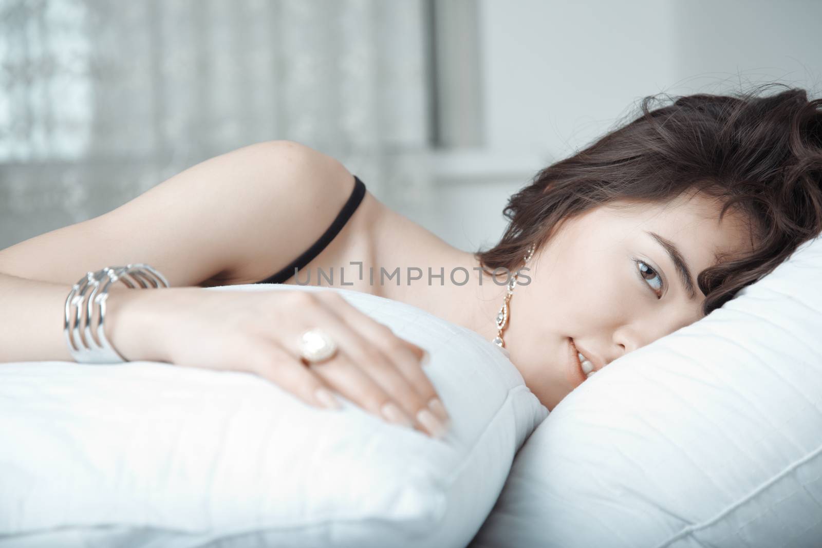 Brunette lady with jewelry laying on the bed