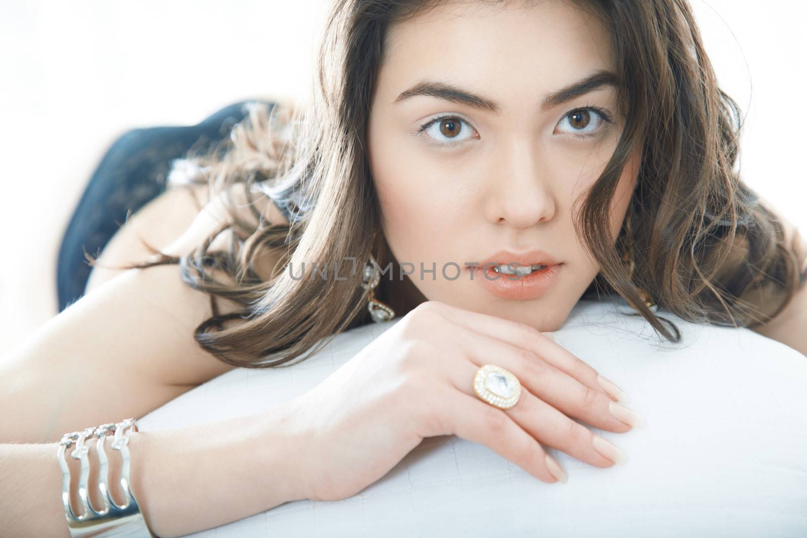 Brunette lady with jewelry laying on the bed