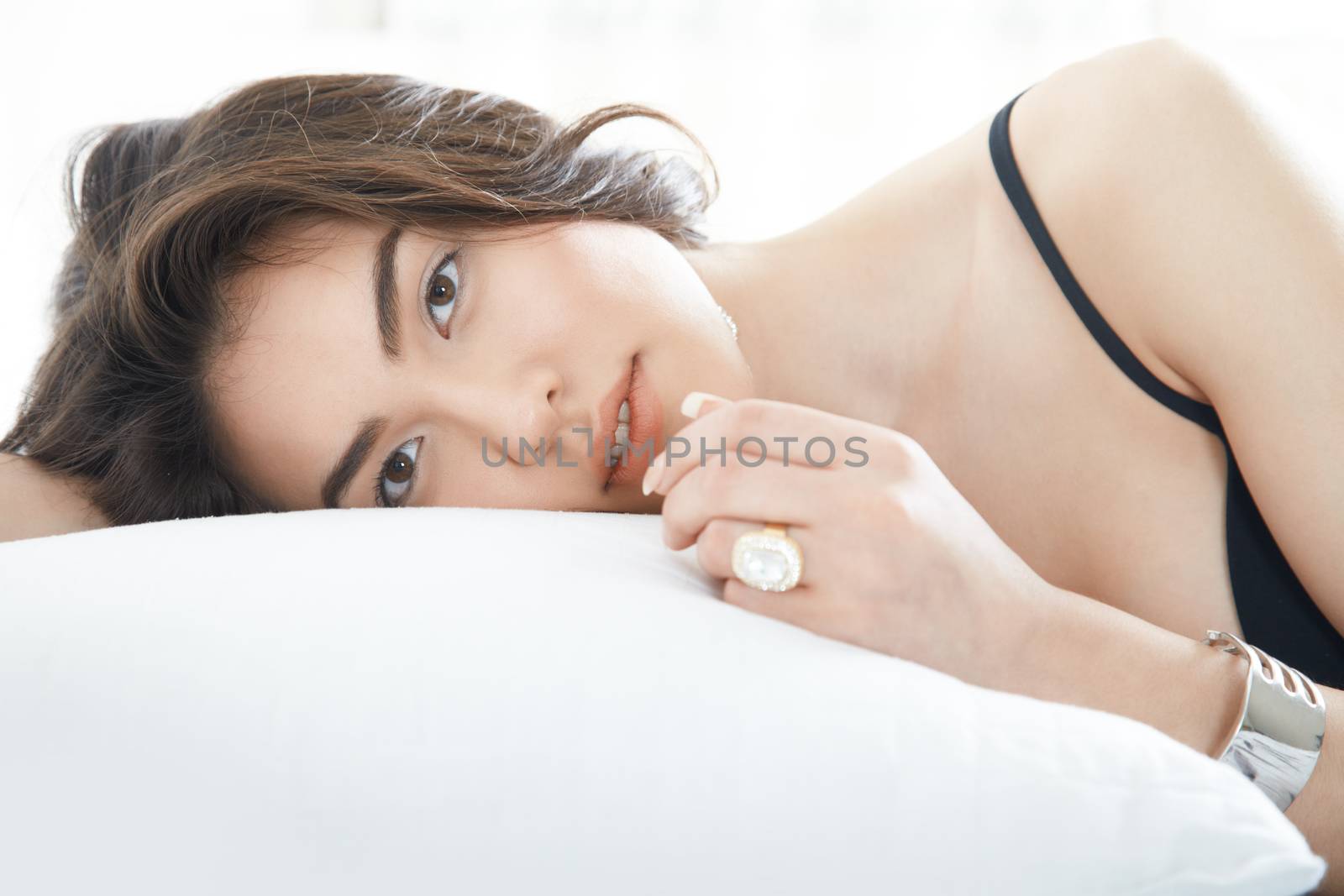 Brunette lady with jewelry laying on the bed