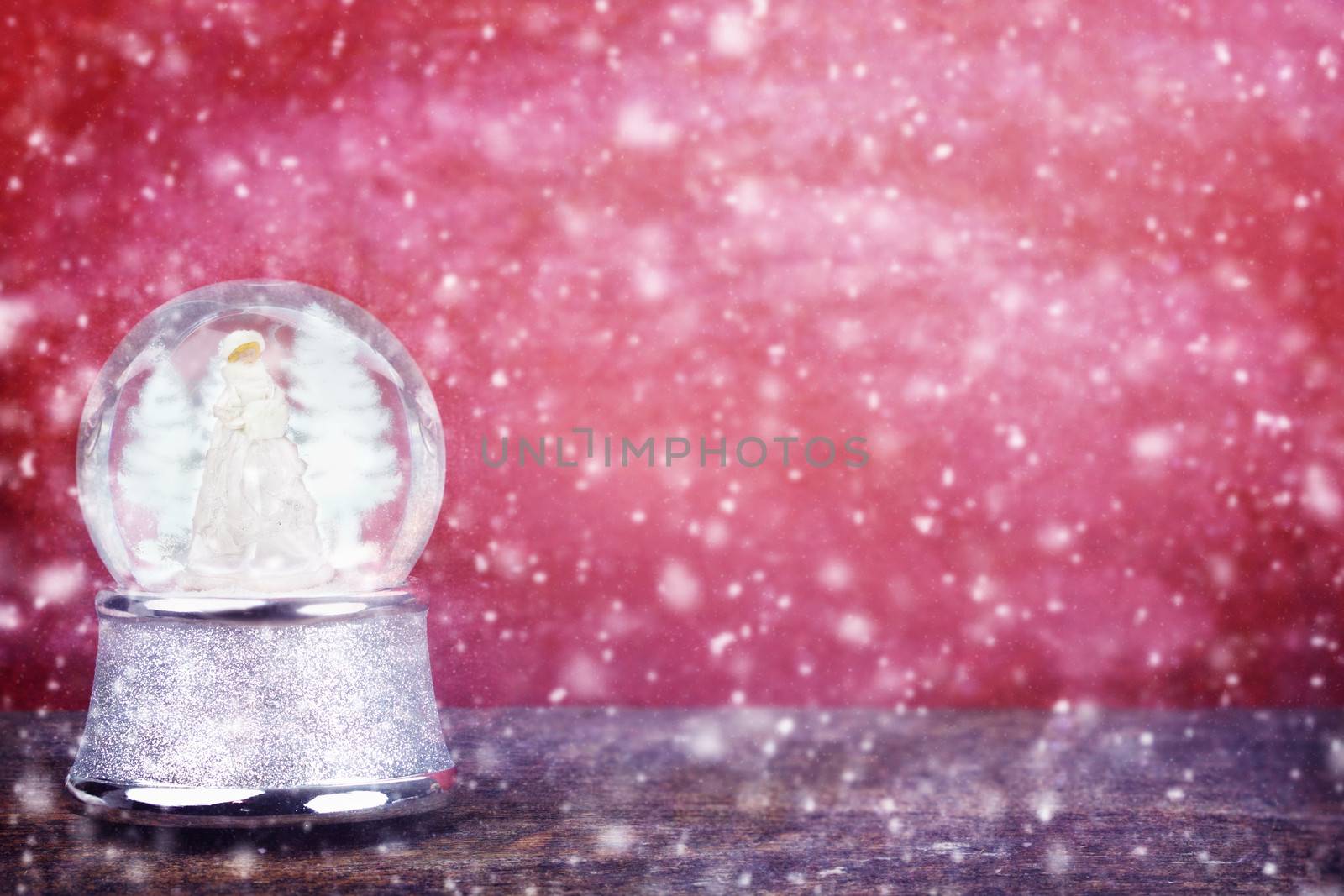 Silver snowglobe against a red background with room for copy space. 