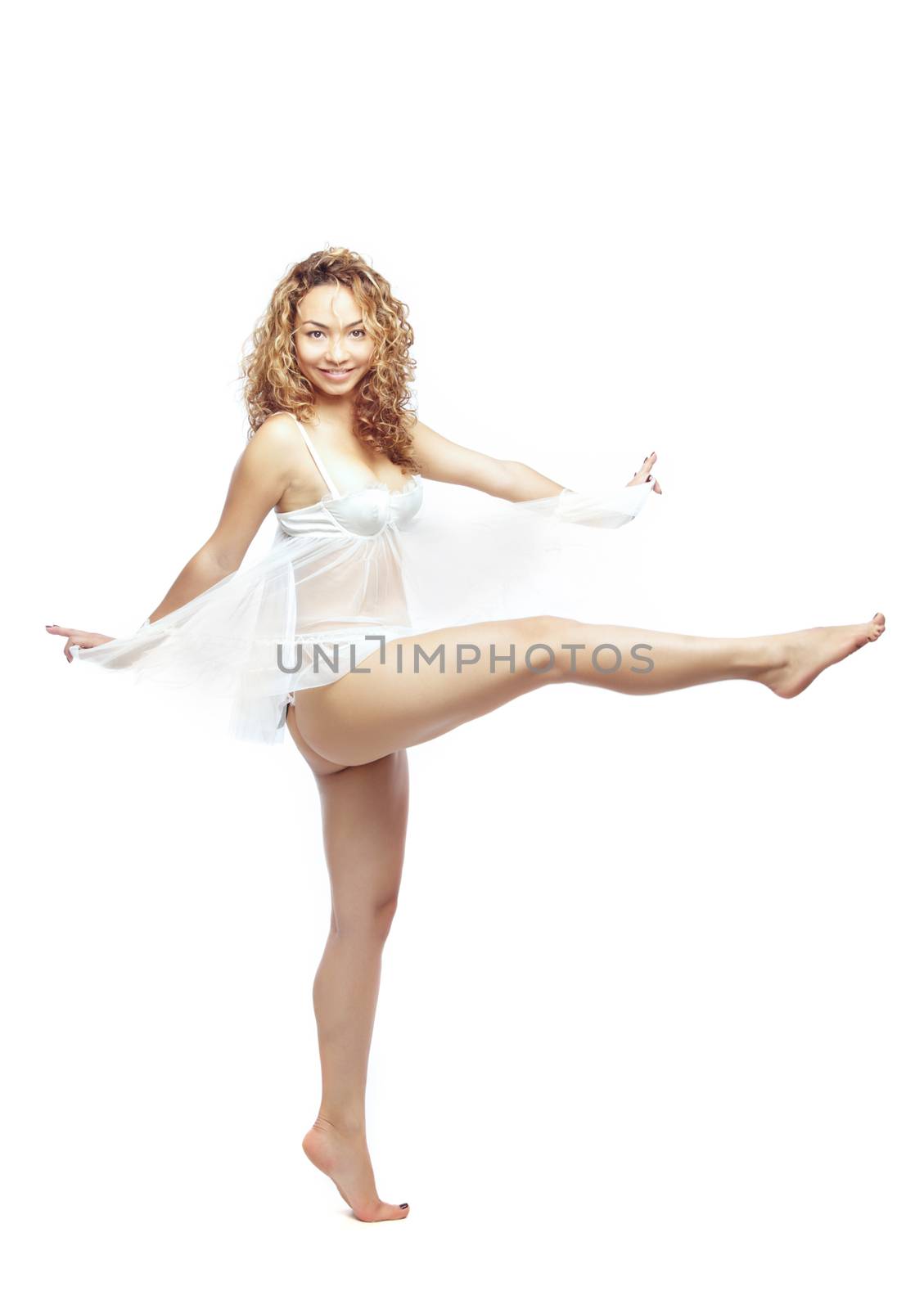 Latin woman with curly hairs swinging her leg and dancing in white peignoir