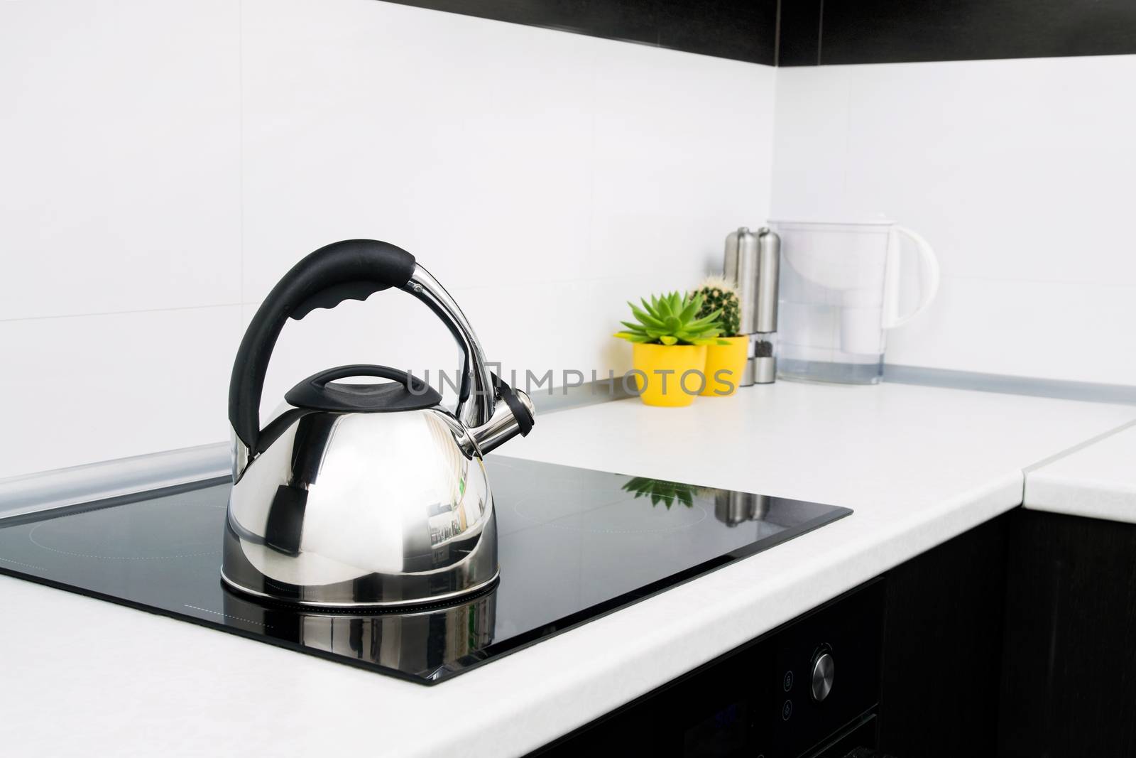 Steel kettle in modern kitchen with induction stove 