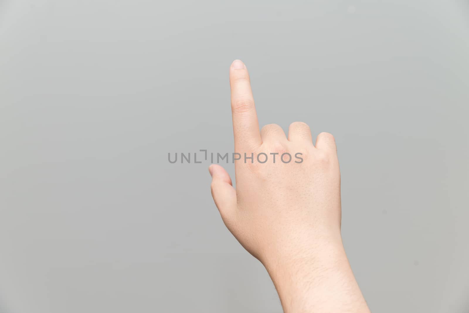Human hand with one finger touching imaginary tablet on gray background