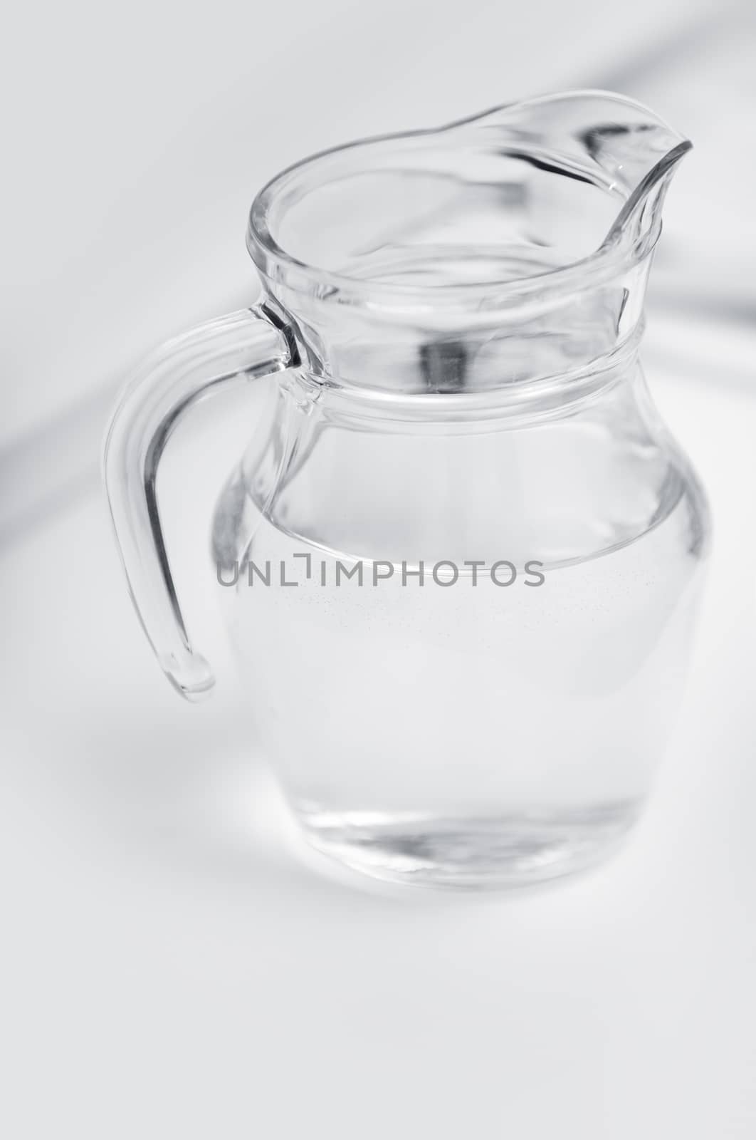 Transparent glass can with water on a table with shadows