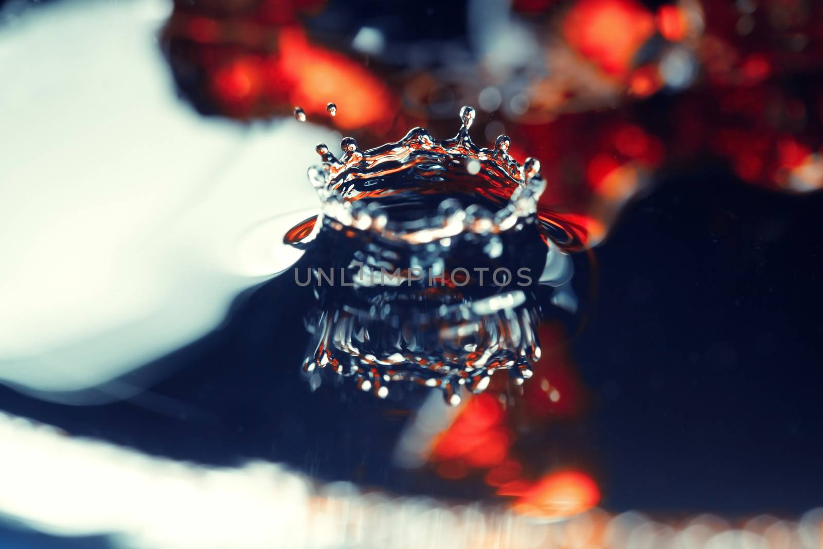 Extremely macro photo of the liquid drop falling on a wet colorful surface