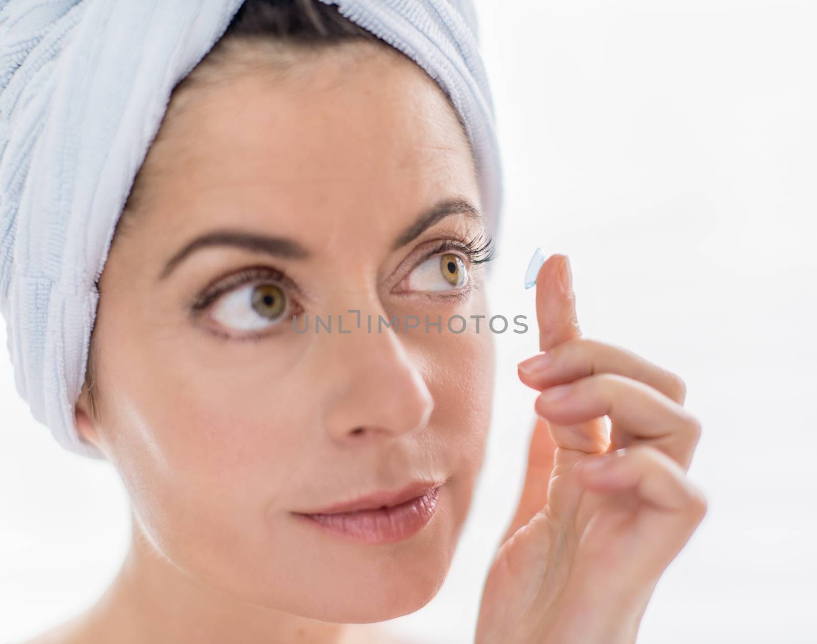portrait of a beautiful mature lady inserting contact lenses