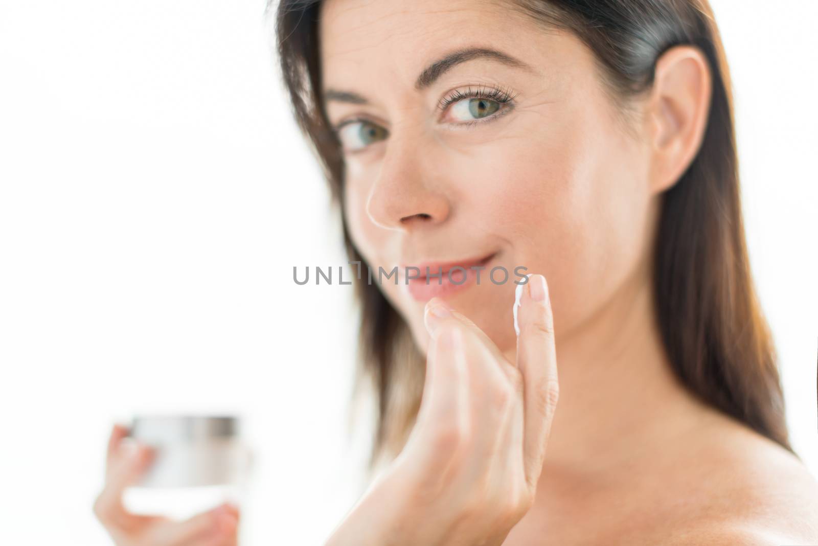 Woman in her forties applying  face cream by julief514