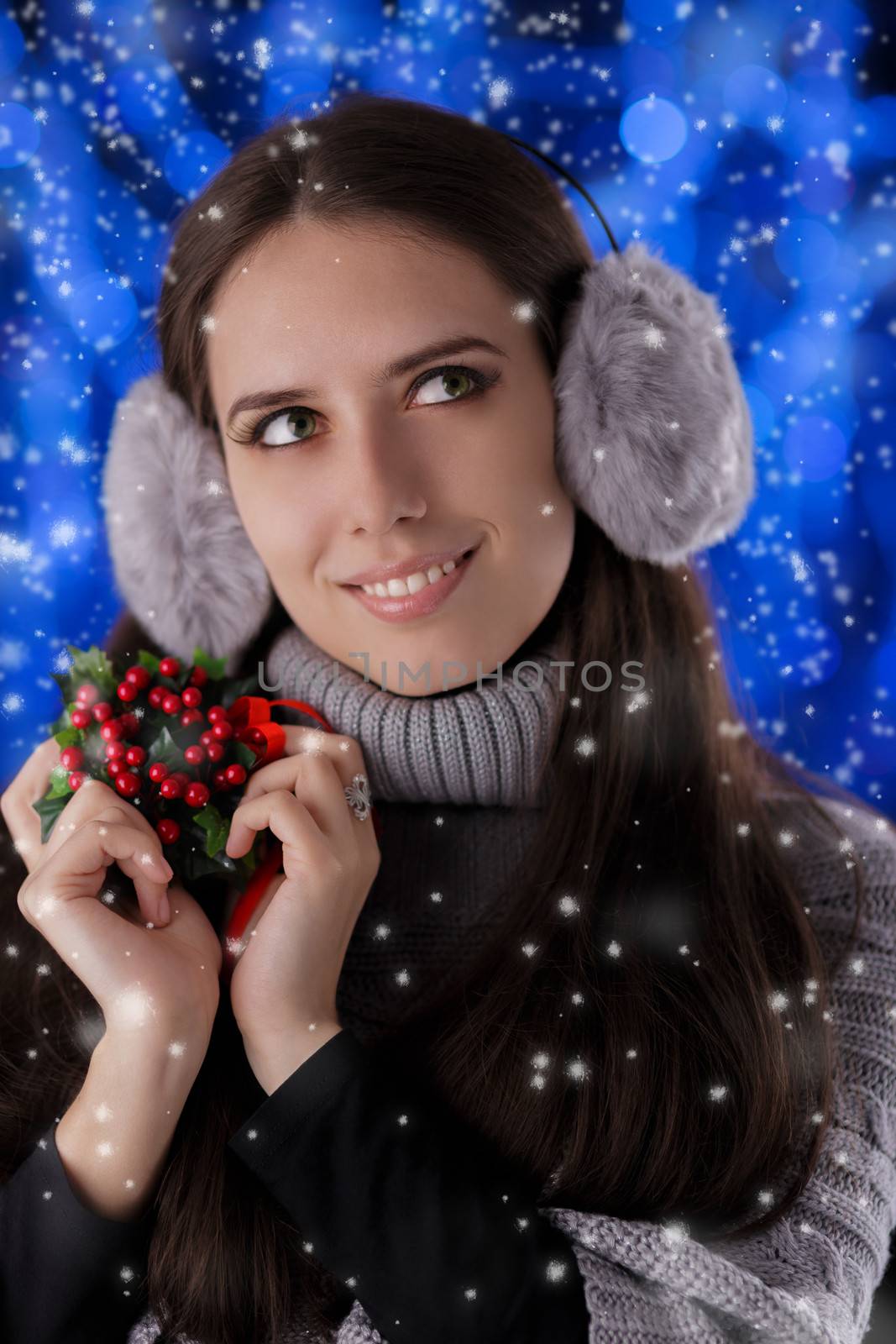 Beautiful girl holding a Christmas decoration with snow falling around her.