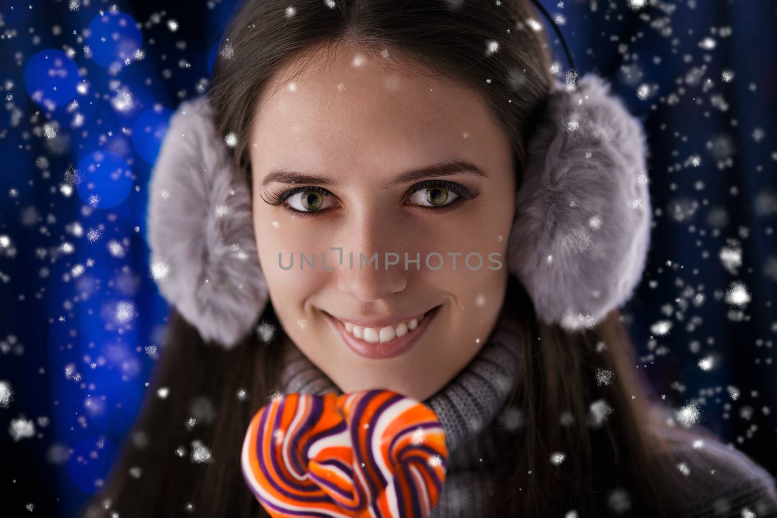 Beautiful girl holding a lollypop with snow falling around her.