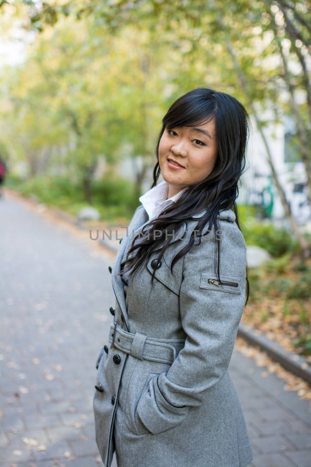 Portrait of beautiful young girl standing on a walk way bonded by trees looking hopeful