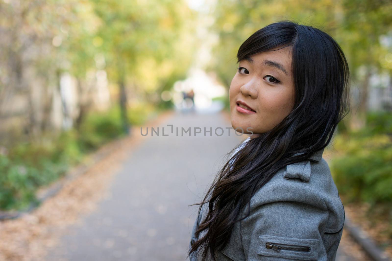 Portrait of beautiful young girl standing on a walk way bonded by trees looking hopeful