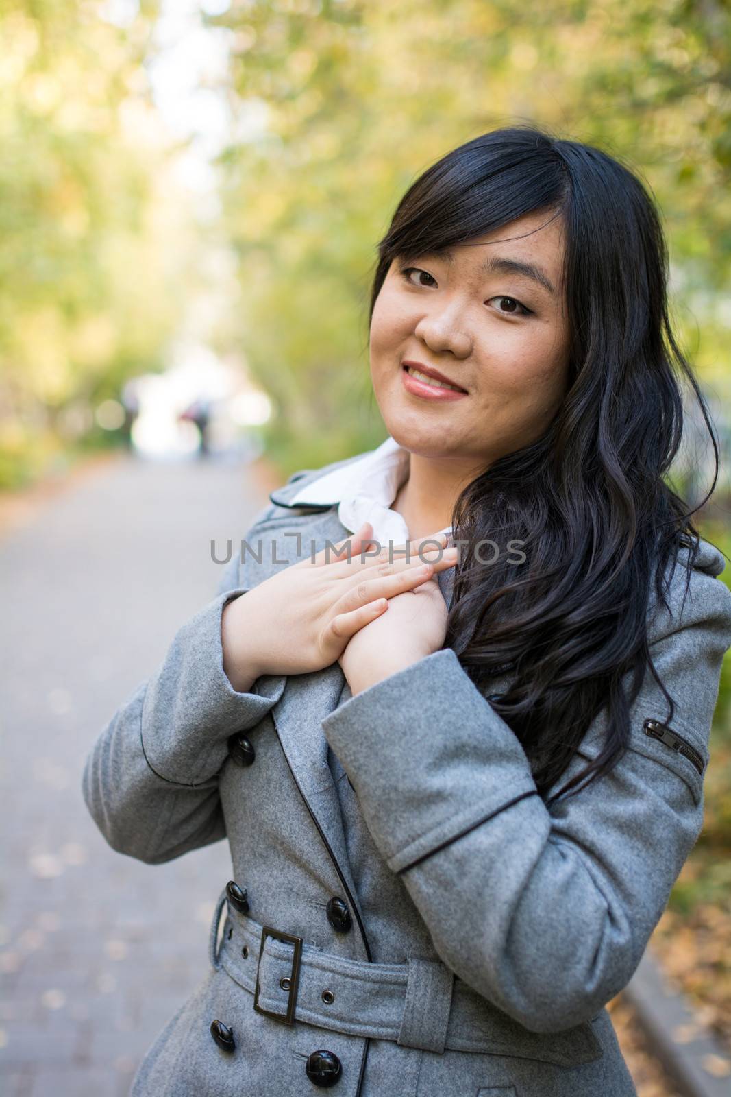 Portrait of beautiful young girl standing on a walk way bonded by trees looking hopeful