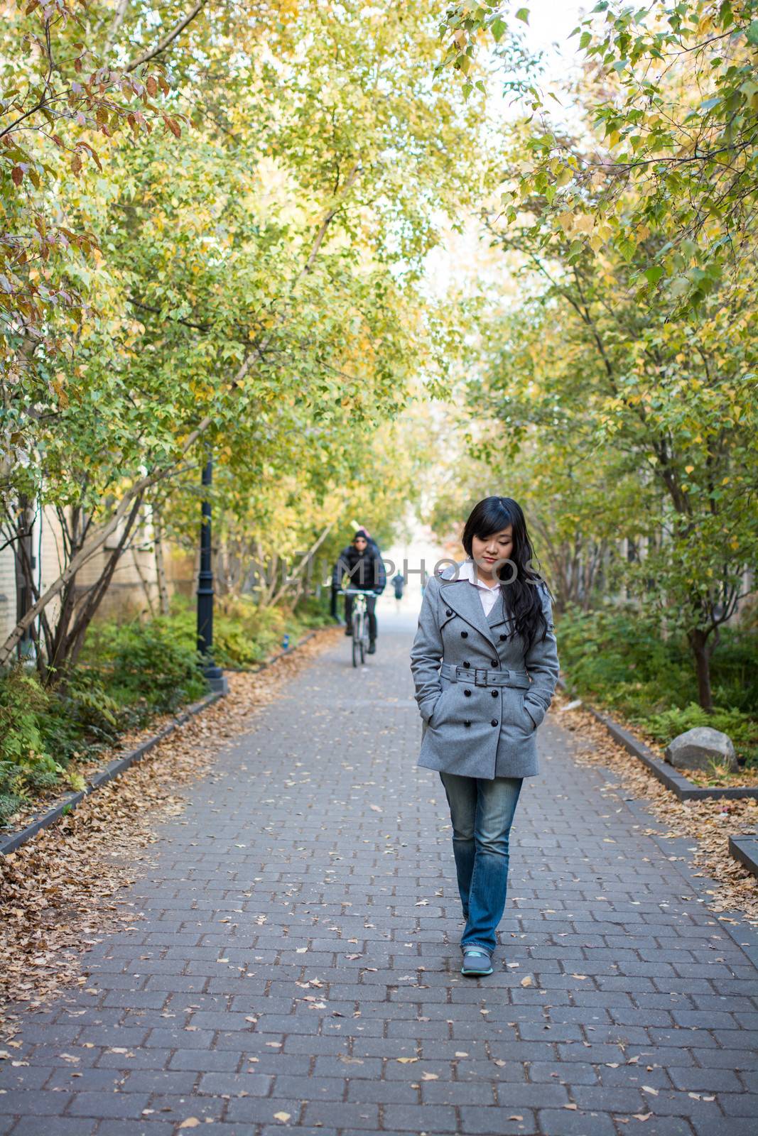 Portrait of beautiful lonely girl walking down a road bonded by trees