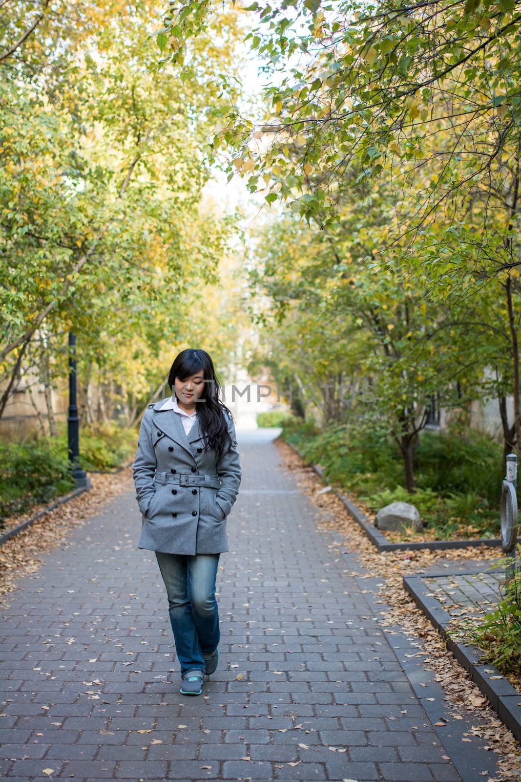 Portrait of beautiful lonely girl walking down a road bonded by trees