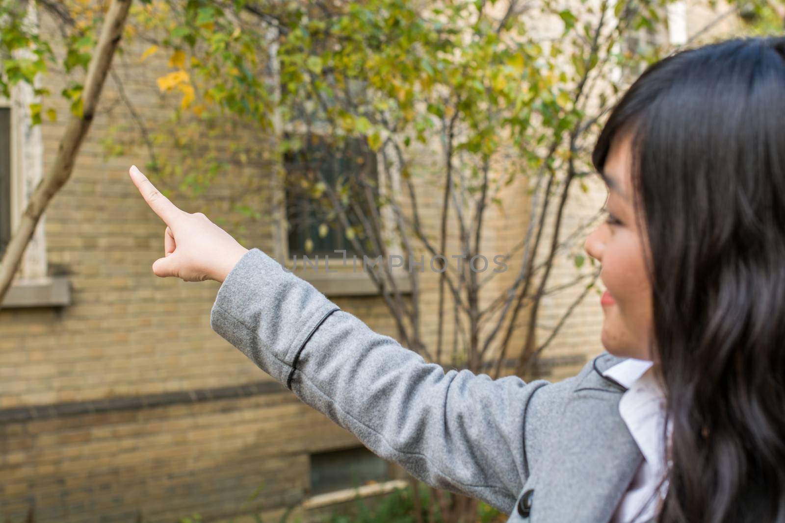 Portrait of young attractive girl pointing at something on the trees at the side of a road