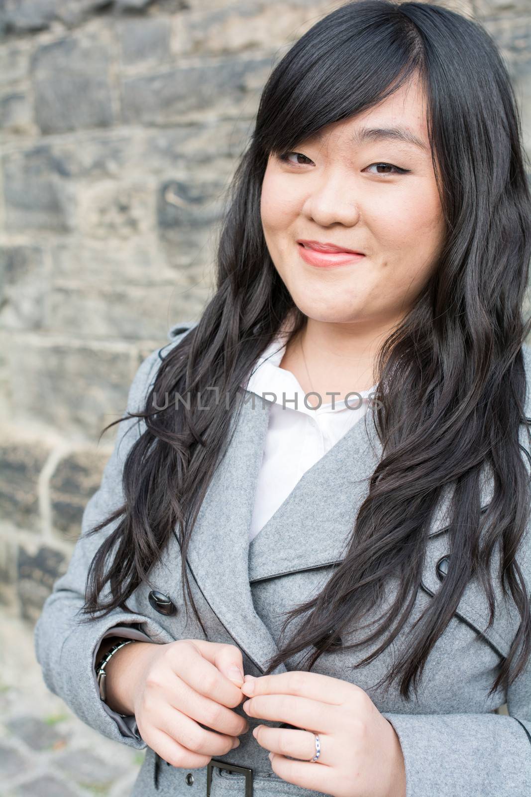 Happy woman by a stone wall by IVYPHOTOS