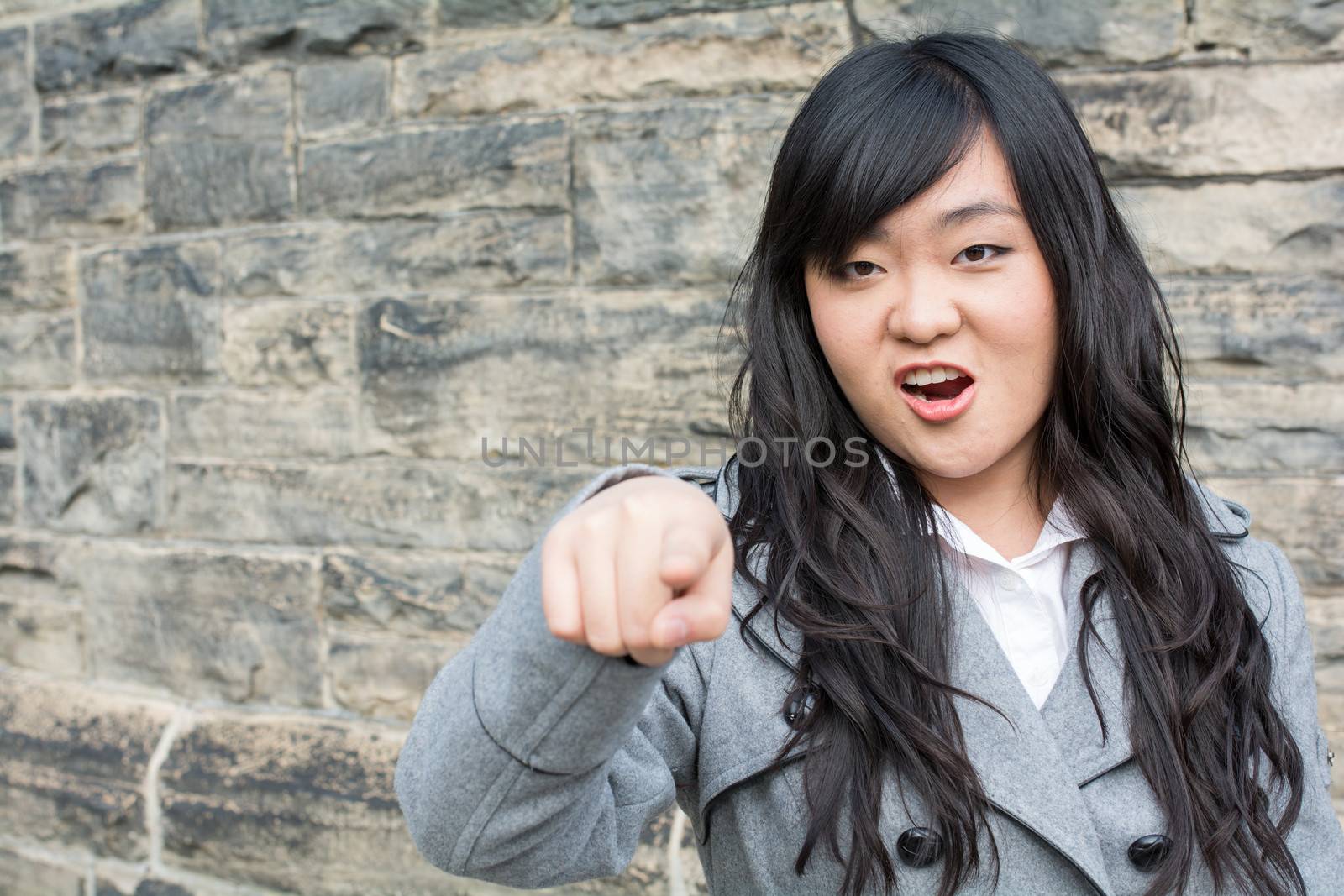 Portrait of young woman in front of a stone wall looking angry