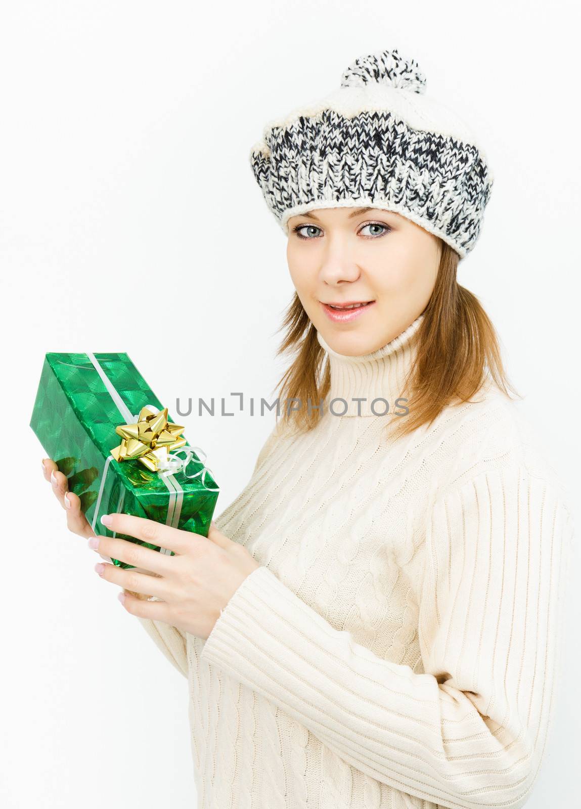 Charming smiling girl in winter cap holding a gift box