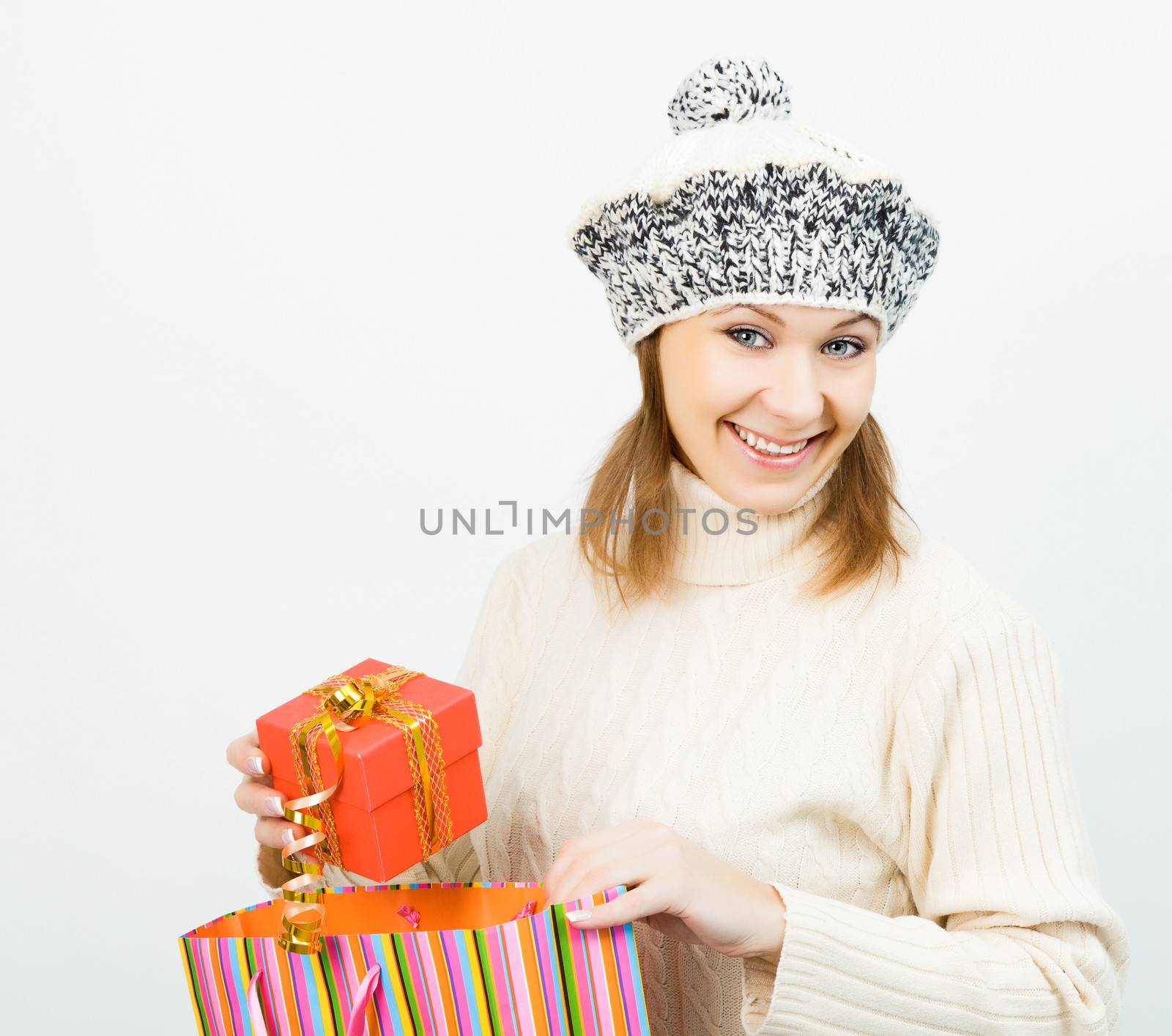 Charming smiling girl in winter cap holding a gift box