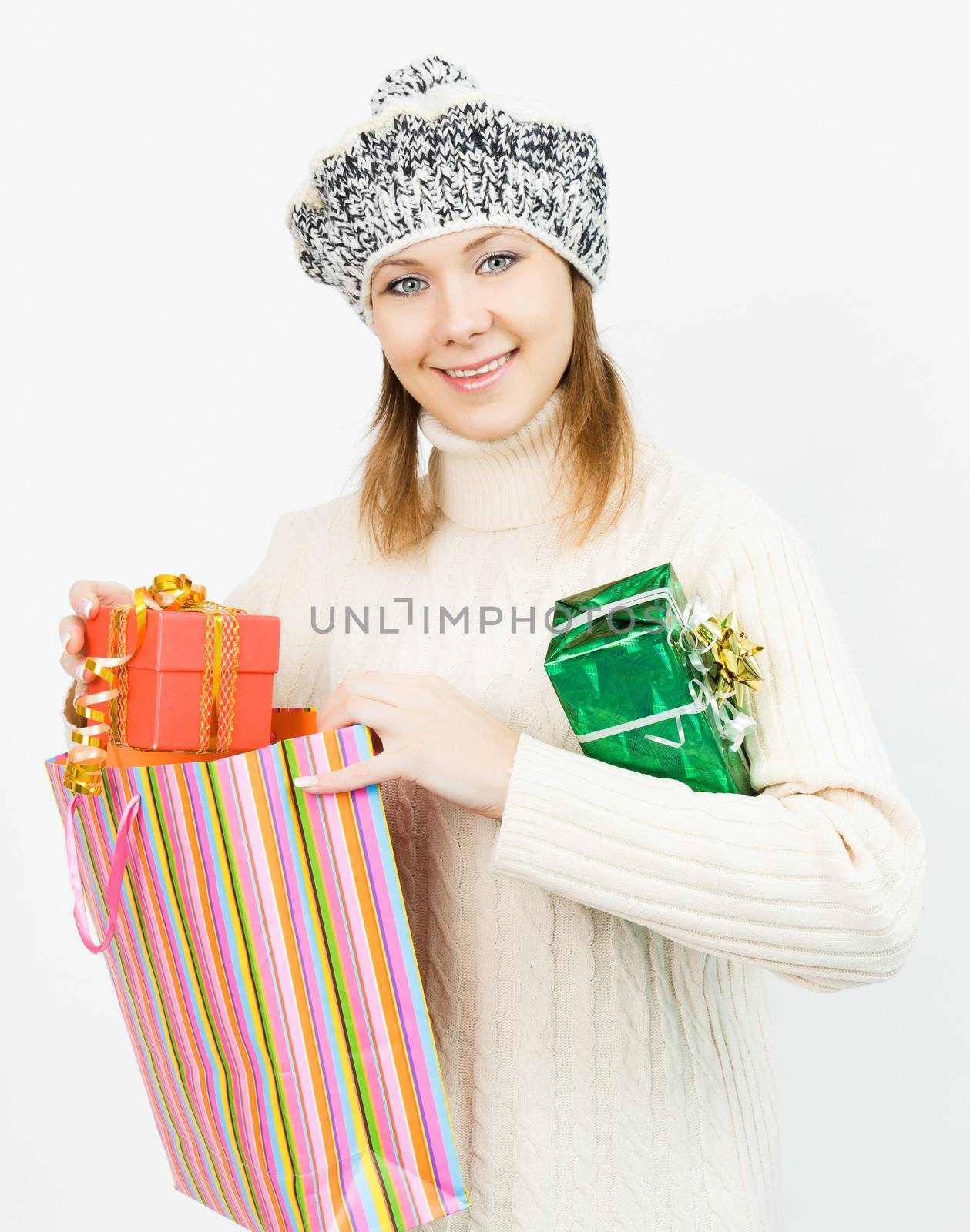 Charming smiling girl in winter cap holding a gift box