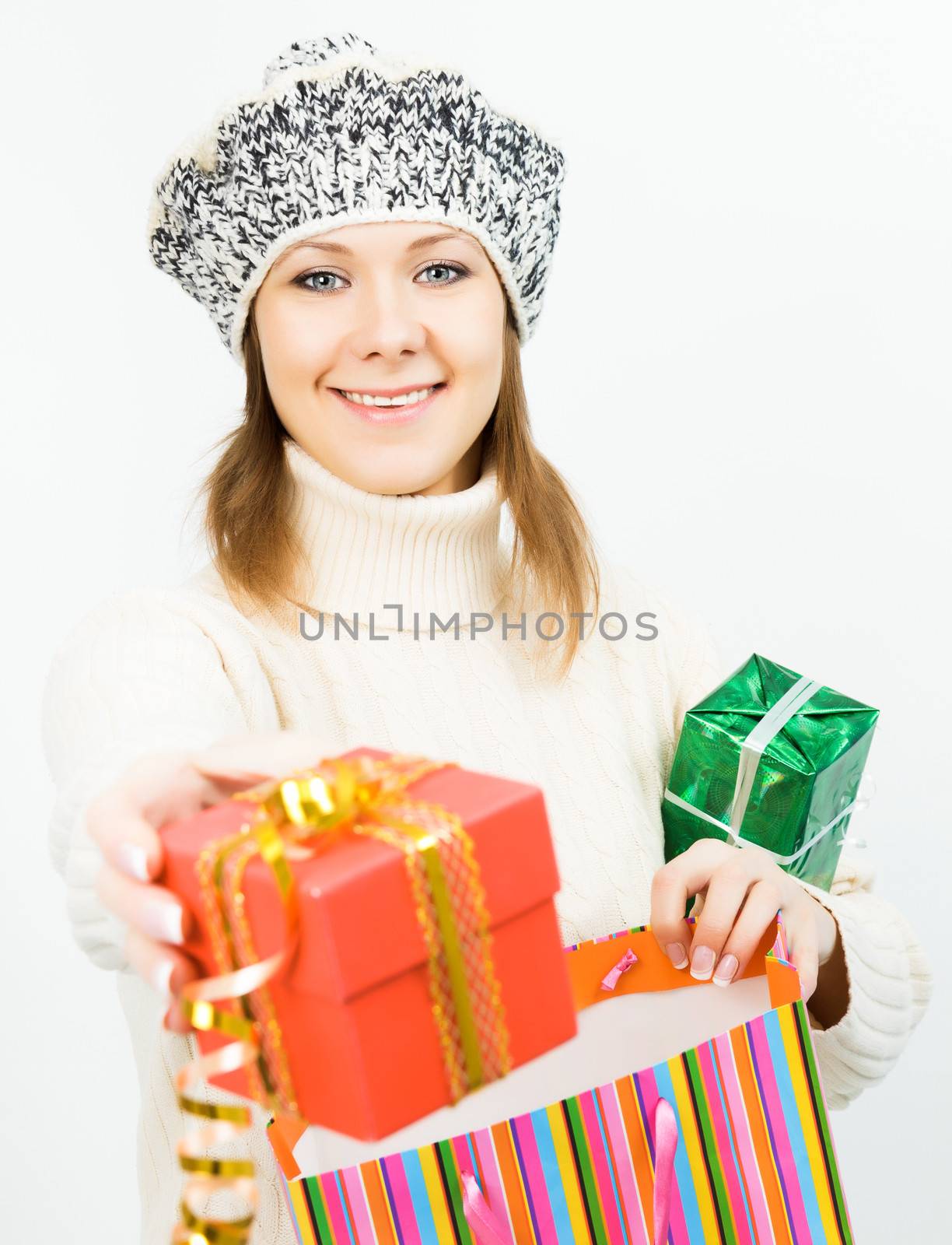 Charming smiling girl in winter cap holding a gift box