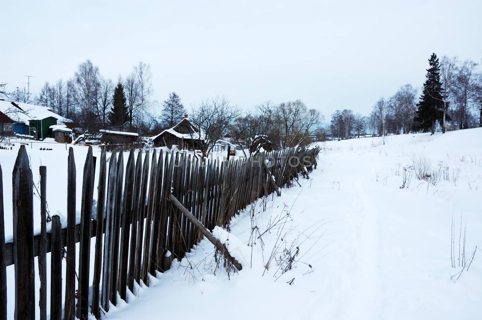 Winter landscape with snowy footpath along the wooden fence