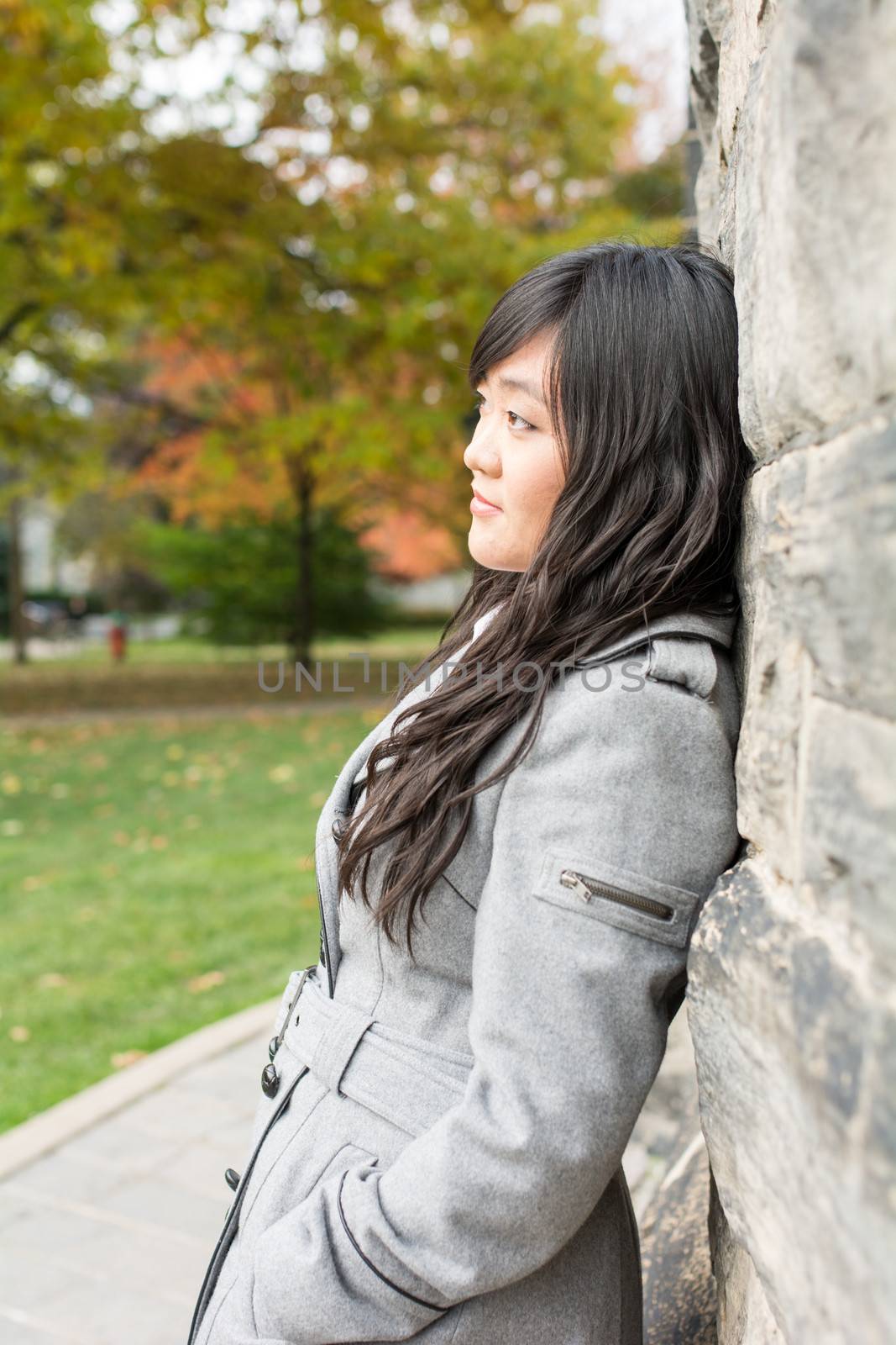 Woman standing against a brick wall by IVYPHOTOS