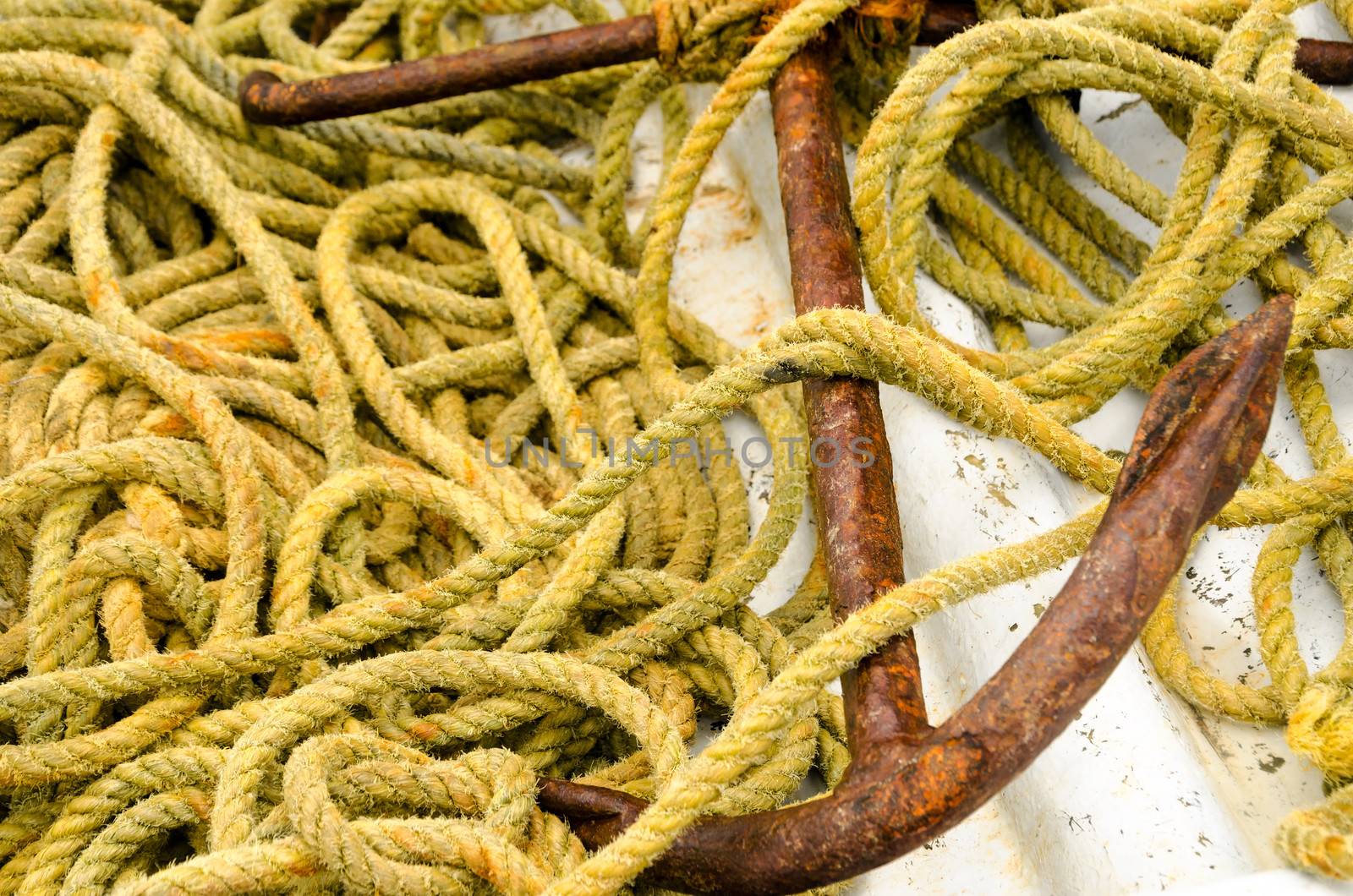 Old rusted anchor and old yellow rope