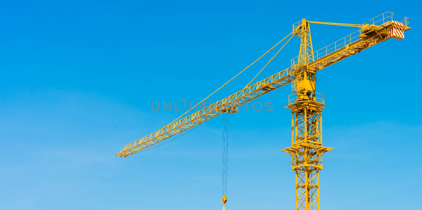 yellow hoisting crane with blue sky in background daylight time