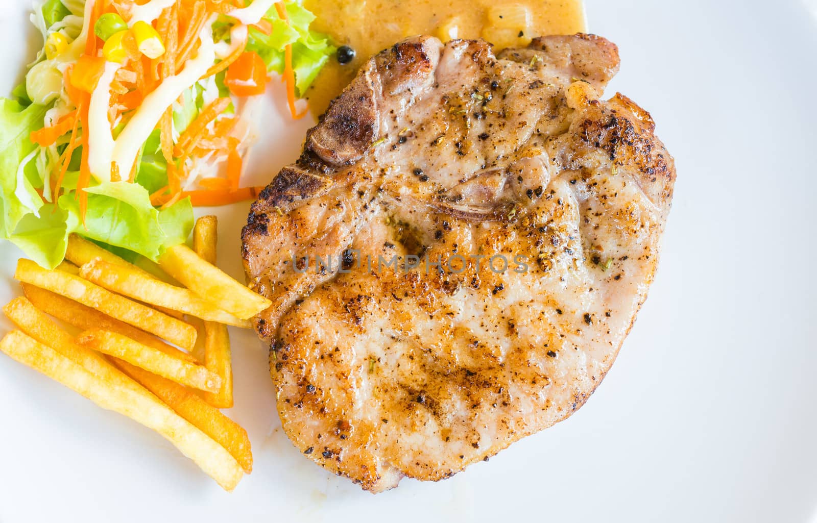 pork steak on white dish with salad and french fries by moggara12