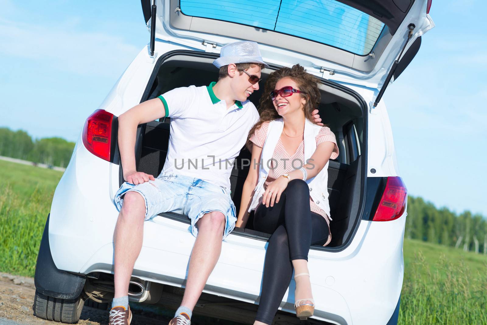 young couple sitting in the open trunk by adam121