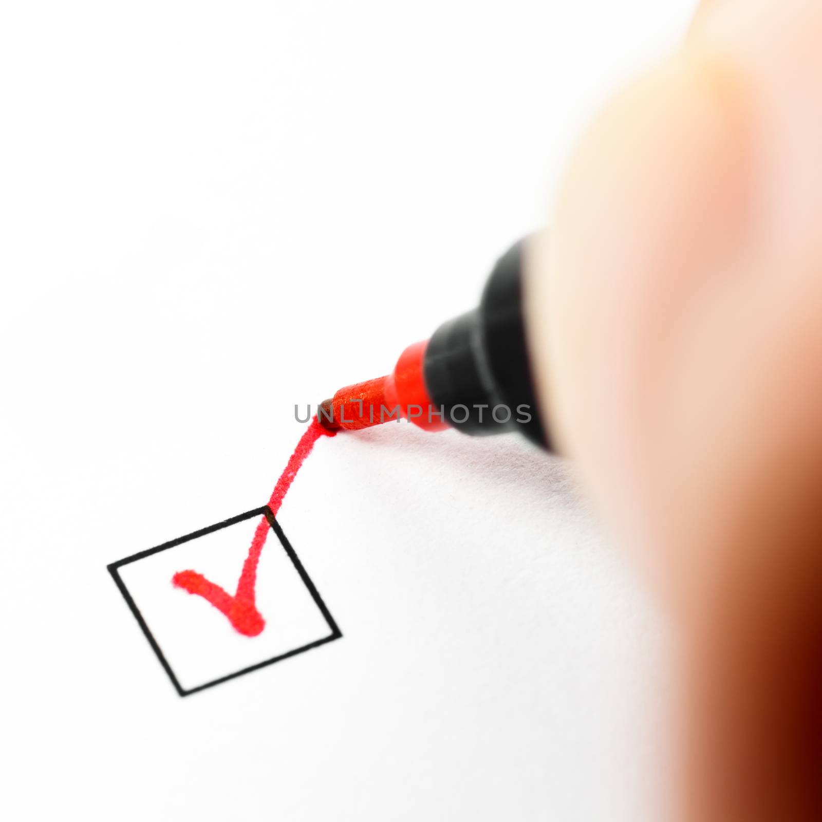 Hand with red pen marking a check box