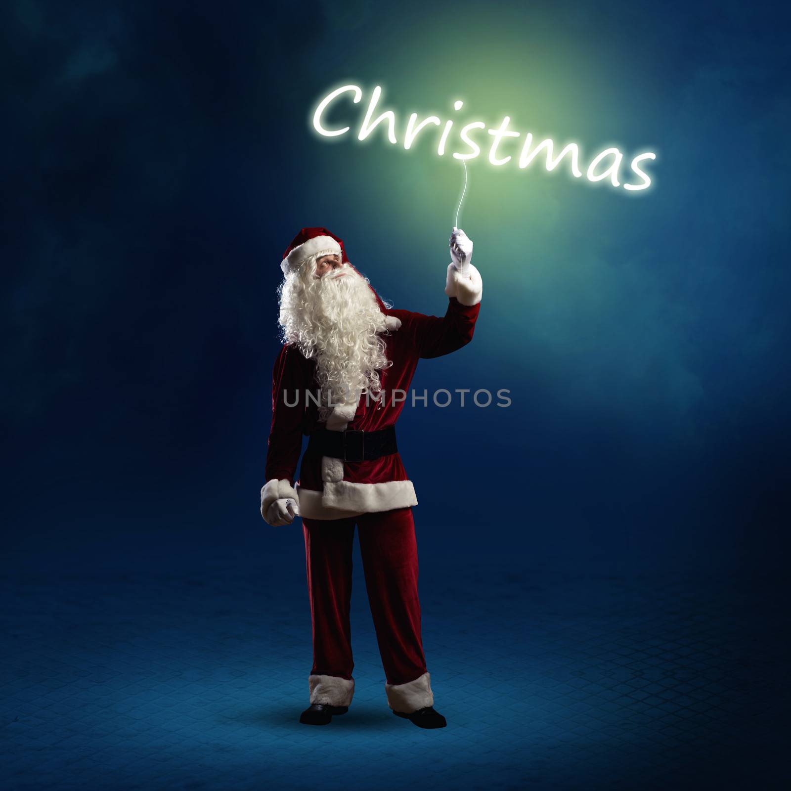 Santa Claus is holding a shining Christmas word sign on a string
