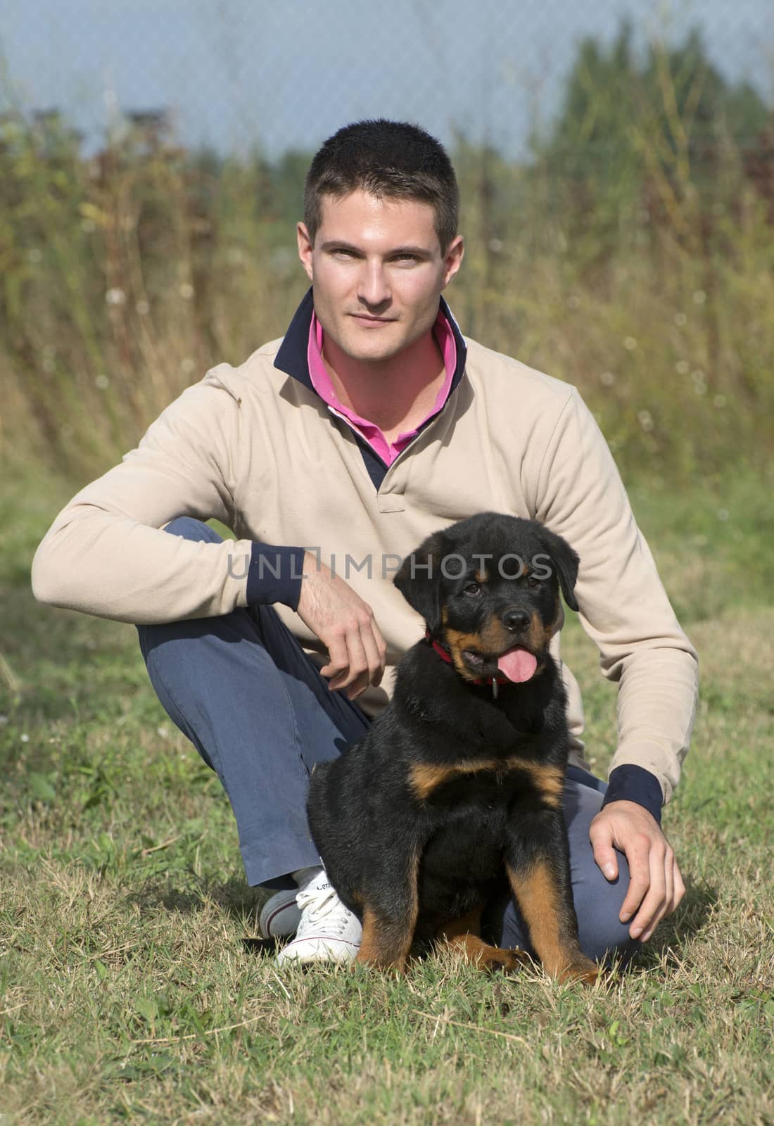 man and puppy rottweiler in a garden