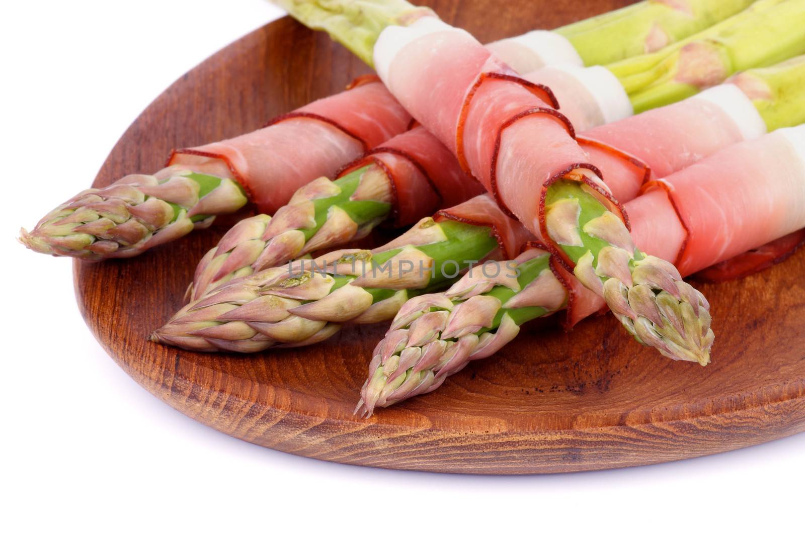 Asparagus Sprouts Wrapped in Smoked Bacon closeup on Wooden Plate