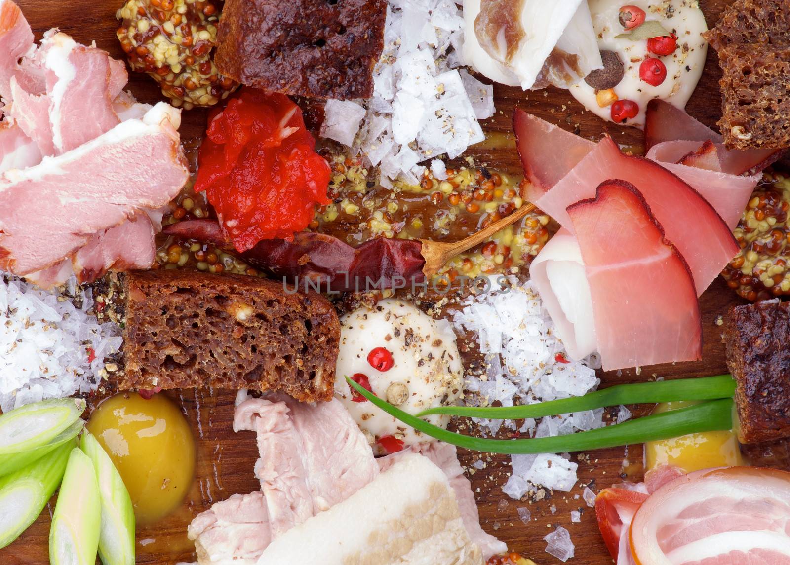 Background of Various Uncooked, Smoked and Boiled Ham with Mustard, Salt, Pepper, Brown Bread, Spring Onion and Spices closeup on Wooden Plate