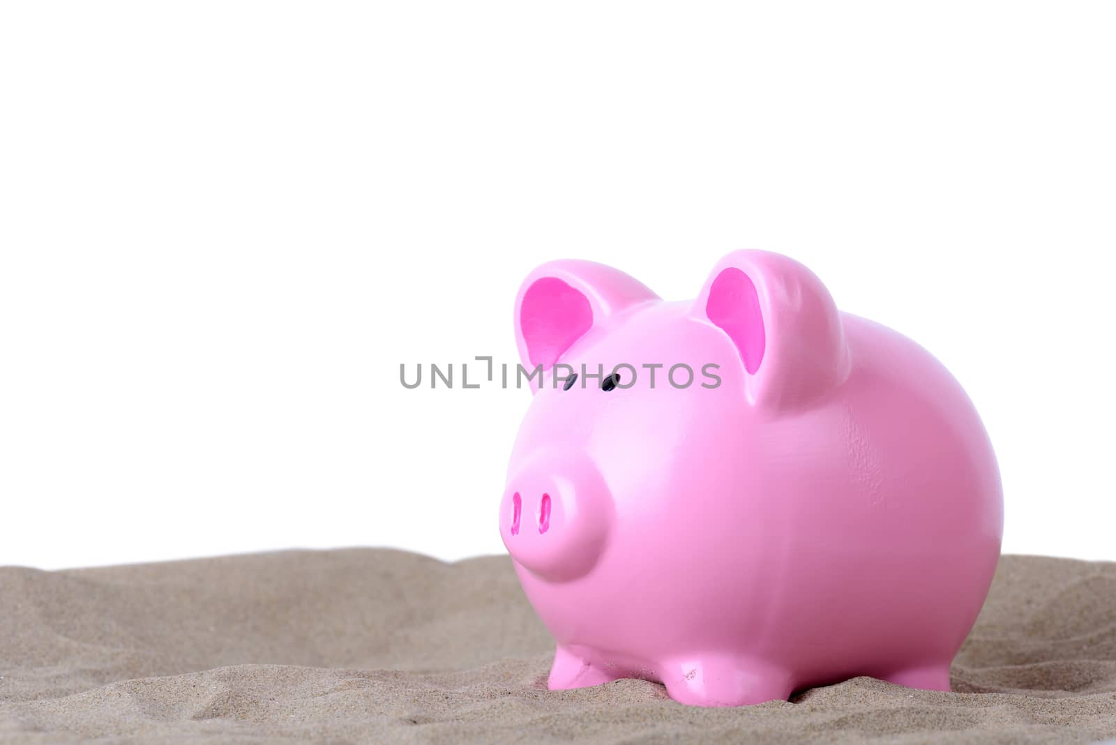 concept of holiday saving piggy bank in sand isolated on white