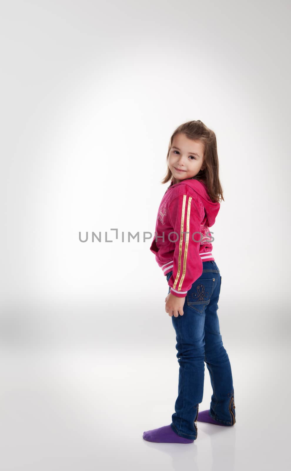 little girl in blue jeans and a red jacket posing standing in the studio