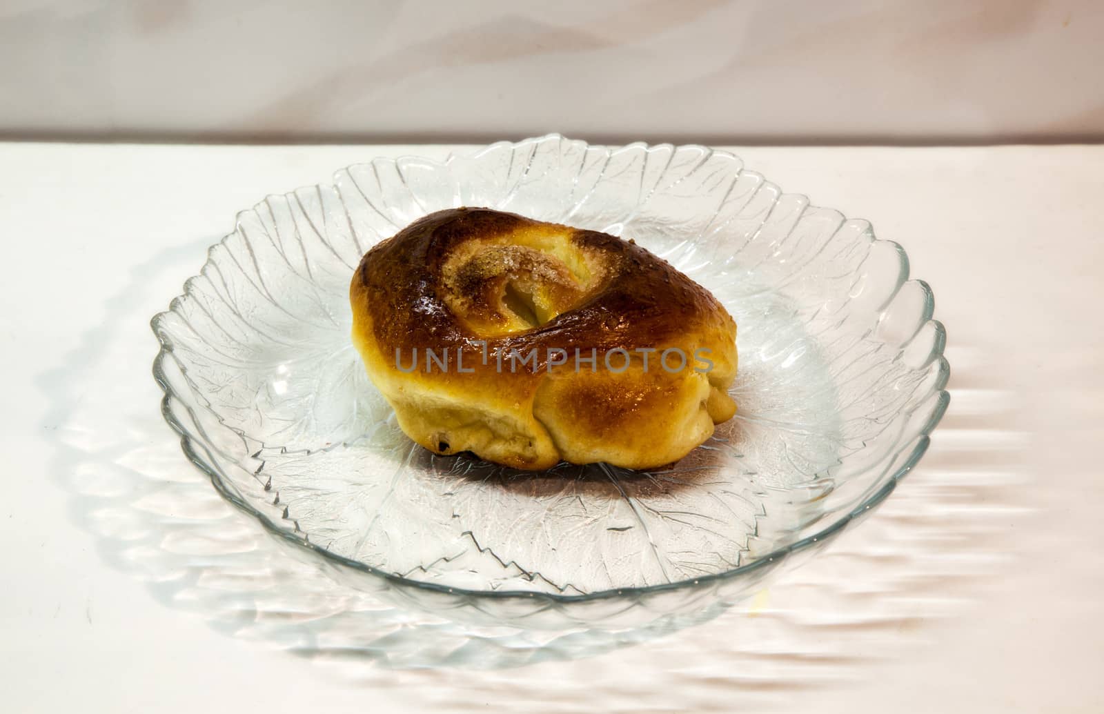 sweet roll lies in a glass dish on a table